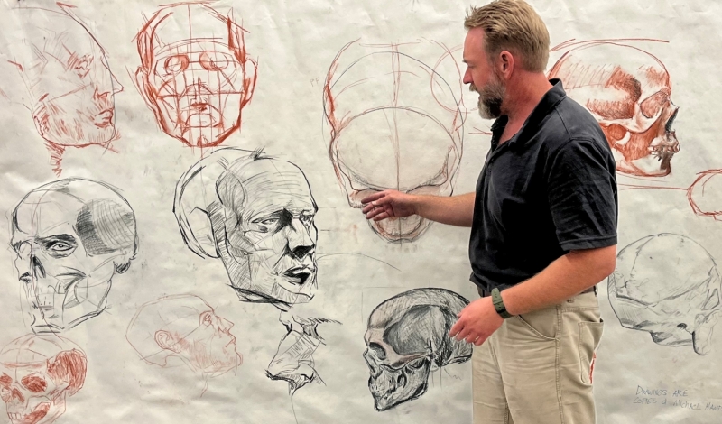 Brandon Smith looking at face drawings on paper