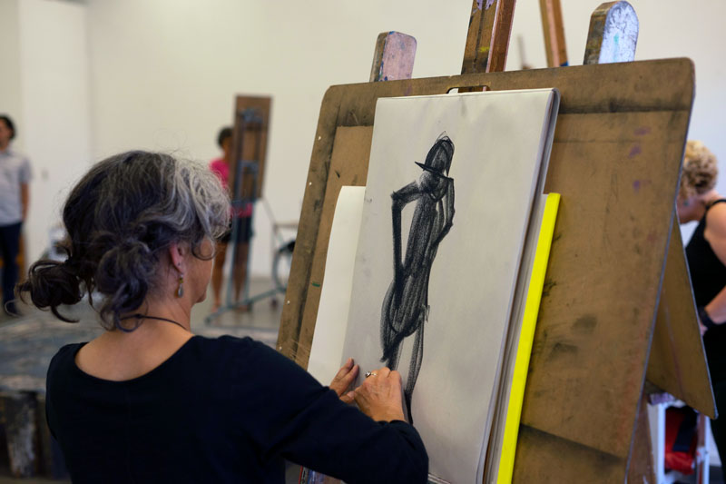 Photograph of person sketching figure on canvas
