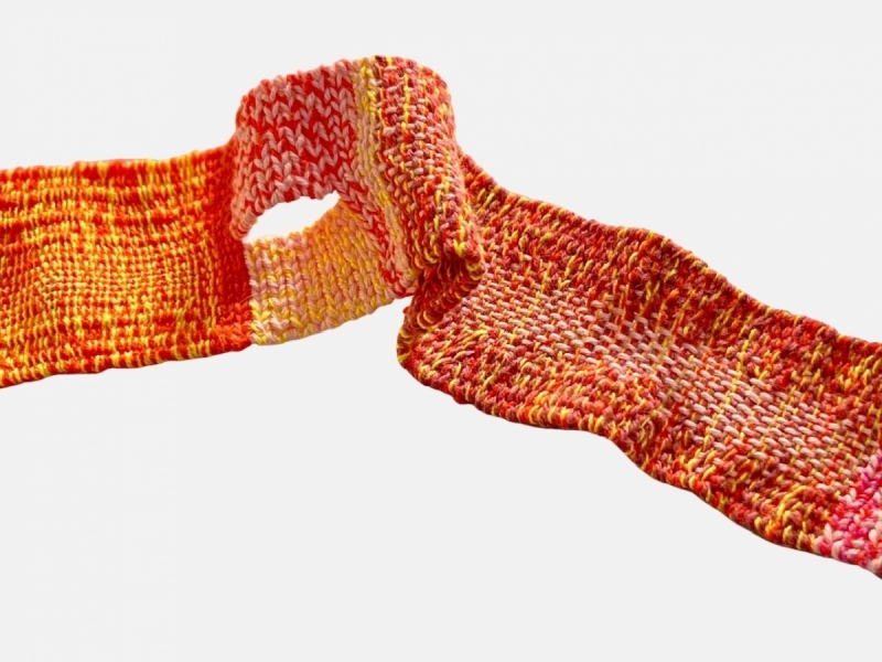 A bright fiery colored strip of weaving on a white background.